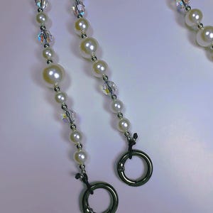 May include: White pearl and crystal beaded lanyard with two silver clasps. TEACHER LANYARD-2 CLASPS 19 INCHES.