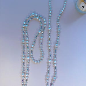 May include: Two white pearl and crystal beaded phone straps with single clasps. The straps are on a white background.  SINGLE CLASP is written on the bottom right corner of the image.