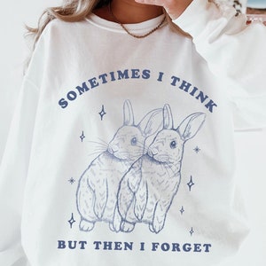 May include: White sweatshirt with a blue graphic of two bunnies and the text "Sometimes I think, but then I forget".