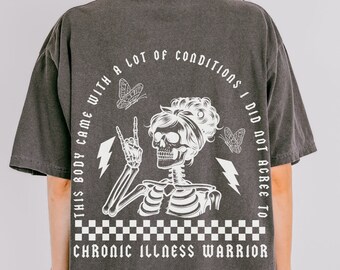 May include: Black t-shirt with a white graphic of a skeleton with a crown of flowers, holding a peace sign and lightning bolts. The text reads "This body came with a lot of conditions I did not agree to. Chronic Illness Warrior."