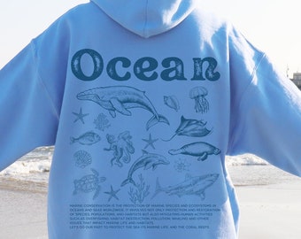 May include: Light blue hoodie featuring a graphic of ocean life and the word "Ocean" in a retro font. The graphic includes a whale, jellyfish, starfish, seahorse, and other marine life. The text below the graphic reads "Marine conservation is the protection of marine species and ecosystems in oceans and seas worldwide. It involves not only protection and restoration of species populations and habitats but also mitigating human activities that impact marine life and its habitats. Let's do our part to protect our sea life, and the coral reefs."