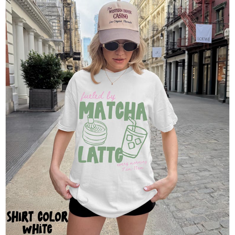 May include: White t-shirt with the text "fueled by MATCHA LATTE" in green and pink. The design includes illustrations of matcha preparation and an iced drink. A beige cap with "The Western House Casino" is also visible.