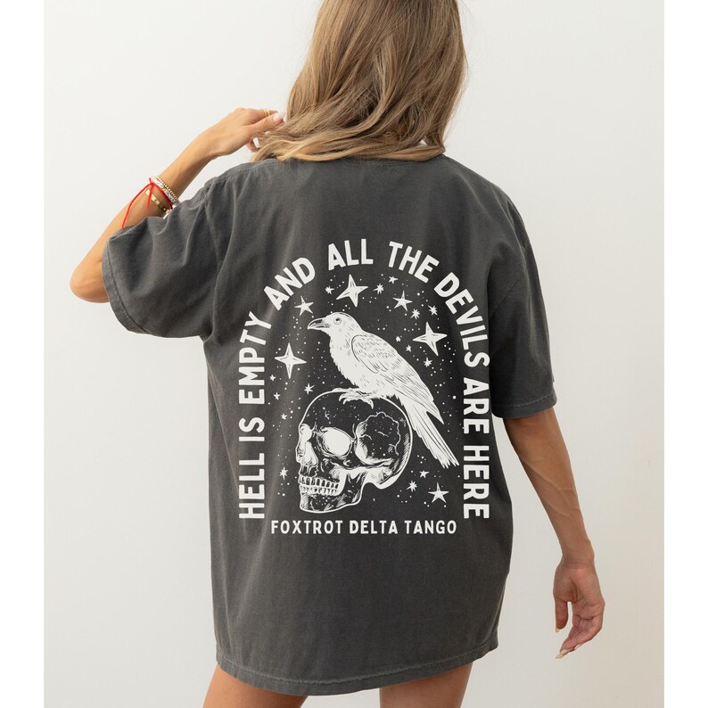 May include: Dark gray t-shirt with a white graphic on the back. The graphic features a skull, a raven, stars, and the text "HELL IS EMPTY AND ALL THE DEVILS ARE HERE" and "FOXTROT DELTA TANGO".