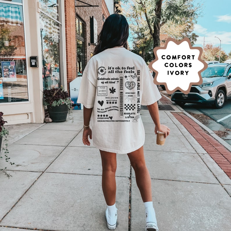 K&ouml;nnte beinhalten: Ein wei&szlig;es T-Shirt mit schwarzem Text und Grafiken. Der Text beinhaltet "it's ok to feel all the feels", "Celebrate minds of all kind", "Embrace Neurodiversity", "See the able not the label", "Your words matter", "Inclusion matters", "We all thrive where different emotions are welcome", "Everyone communicates differently", "Regulate", "Listen". Das Shirt ist mit "Comfort Colors Ivory" gekennzeichnet.