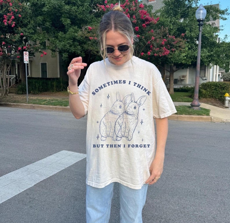 May include: A light beige t-shirt with a graphic of two rabbits and the text "Sometimes I think but then I forget".