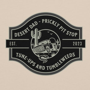May include: Black and white logo with a desert scene. It says "Desert Dad - Prickly Pit Stop" with a vintage truck, cactus, and snake. The text below says "Tune-Ups and Tumbleweeds" and "Est. 2023".