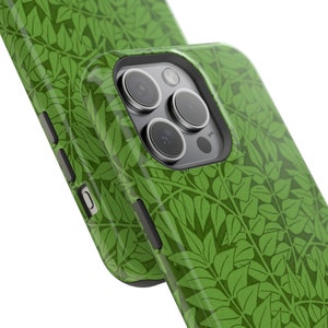 Puede incluir: Funda de teléfono verde con un patrón de hojas. La funda tiene una protuberancia de cámara elevada con tres lentes.
