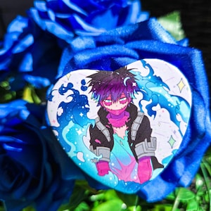 May include: A heart-shaped button featuring a character with purple hair and a black jacket, set against a blue and turquoise background. The button is surrounded by vibrant blue roses and green foliage.