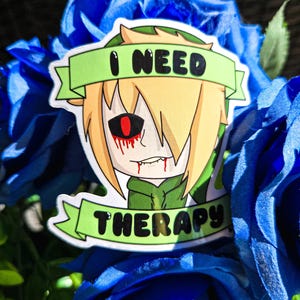 Puede incluir: Una pegatina con un personaje de estilo anime con pelo rubio, una chaqueta verde y un ojo rojo. La pegatina tiene el texto "I NEED THERAPY" en una pancarta verde. La pegatina está rodeada de rosas azules.