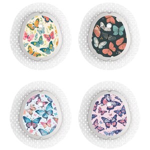 Op de afbeelding: Vier ronde, witte pleisters met verschillende vlinderontwerpen. De ontwerpen omvatten een geel en oranje vlinderpatroon, een zwart en turquoise vlinderpatroon, een blauw en roze vlinderpatroon en een roze en paarse vlinderpatroon.