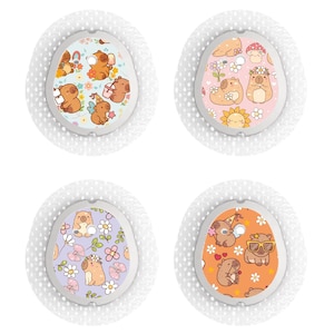 May include: Four small, round decorative patches with white, dotted borders. Each patch features a different design with cartoon animals, flowers, and other elements in various colours. The patches are set against a white background.
