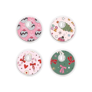 Könnte beinhalten: Vier runde Designs zum Thema Weihnachten. Jedes hat einen weißen Rand und ein zentrales Loch. Die Designs umfassen rosa und grüne Ornamente, einen Weihnachtsbaum mit dem Text "HO HO", Zuckerstangen, Herzen, Schleifen und Sterne.
