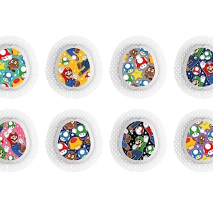 Puede incluir: Ocho artículos circulares con bordes blancos, cada uno con un diseño diferente y colorido de Super Mario Bros. Los diseños presentan a Mario, Luigi, champiñones, estrellas y otros elementos del juego sobre fondos estampados. Tienen un borde texturizado y punteado.