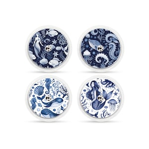 Könnte beinhalten: Vier runde Aufkleber mit einem blauen und weißen Design mit Meerjungfrauen, Seepferdchen, Walen und Quallen. Die Aufkleber sind für die Verwendung auf medizinischen Geräten konzipiert.