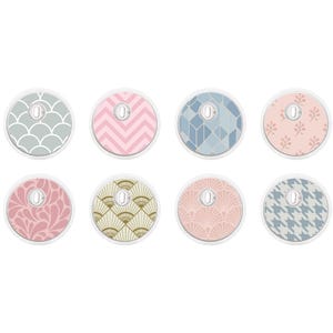 Puede incluir: Ocho cubiertas circulares de plástico con una ranura rectangular central, cada una con un patrón distinto que incluye líneas festoneadas, chevrones rosas, formas geométricas azules, ramitas florales, cachemir rosa, motivos de abanicos dorados, conchas rosas y un patrón de pata de gallo azul.