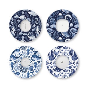 May include: Four circular adhesive patches for medical devices, each featuring a blue and white underwater theme. The designs include illustrations of mermaids, whales, seahorses, jellyfish, coral, and seashells on a dark or light blue background.