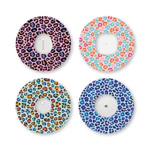 May include: Four circular adhesive patches for continuous glucose monitors, each featuring a distinct leopard print pattern in vibrant color combinations including pink, orange, teal, and blue, surrounding a central white circular device.