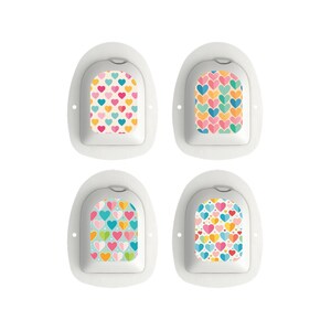 May include: Four white medical patches featuring heart patterns. Each patch displays a unique arrangement of hearts in pink, blue, yellow, and orange. The patches have a curved top and a flat base, suitable for medical use.