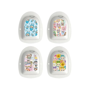 Può includere: Quattro cerotti medici bianchi con disegni di cartoni animati colorati. I disegni includono personaggi blu, una varietà di personaggi, un gruppo di personaggi in un'auto e personaggi con girasoli. Ogni cerotto ha un bordo bianco e una forma arrotondata.