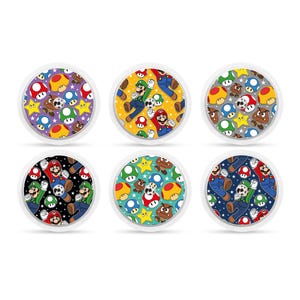 Puede incluir: Seis pegatinas redondas con un patrón repetido de Mario, Luigi, estrellas y setas en varios colores, incluidos rojo, verde, azul, amarillo y negro.