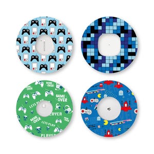 Könnte beinhalten: Vier kreisförmige Klebepflaster für medizinische Sensoren, jedes mit einem einzigartigen Gaming-Muster. Die Designs umfassen schwarze Gamecontroller und Handheld-Konsolen auf Hellblau, blaue Pixelquadrate, grüne Gaming-Symbole und Retro-Arcade-Grafiken.