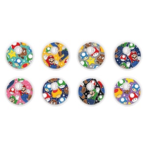 May include: Eight colorful round stickers featuring a repeating pattern of Mario, Luigi, and other characters from the Super Mario Bros. video game series. The stickers are designed to be applied to the Joy-Con controllers for the Nintendo Switch.