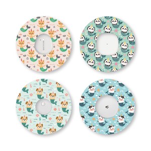 May include: Four circular adhesive patches for medical devices, each featuring a different pattern of cartoon animals as mermaids with unicorn horns. The designs include orange cats, pandas, dogs, and cows on light-colored backgrounds.