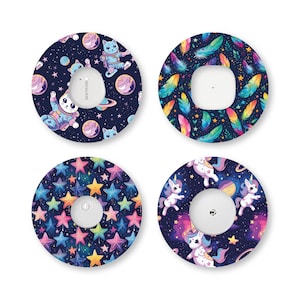 May include: Four circular adhesive patches for medical devices. One features cats in space suits with planets, one has colorful feathers on a dark background, one displays a pattern of multi-colored stars, and one shows unicorns in space.