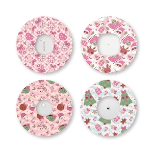 May include: Four circular adhesive patches for medical devices, each featuring a distinct holiday pattern. Designs include pink ornaments, Santa Claus with reindeer, festive hot cocoa mugs, and Christmas trees with gifts on a wavy background.