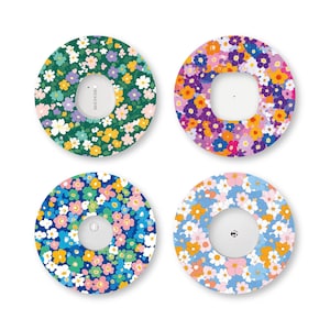 May include: Four circular adhesive patches for continuous glucose monitors, each featuring a distinct floral pattern. The designs include a dark green background, a vibrant multi-colored floral print, a blue base, and a light blue floral motif.