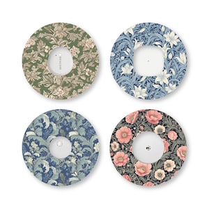 May include: Four circular adhesive patches for a Dexcom continuous glucose monitor. Each patch features a distinct floral pattern: one in olive green, one in blue and white lilies, one in dark blue foliage, and one in pink poppies on a black background.