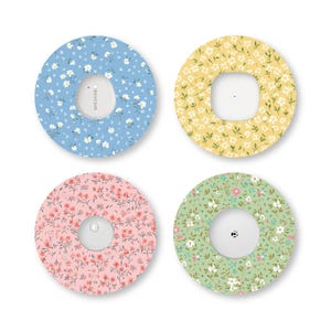May include: Four circular adhesive patches for medical sensors, each featuring a distinct floral pattern. The colors include light blue, yellow, pink, and green, all decorated with small white and colored flowers. The text Dexcom is visible.
