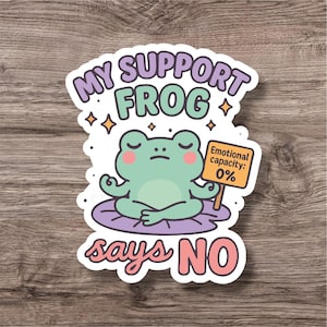 Puede incluir: Una pegatina con una rana de dibujos animados en posición de meditación sobre una hoja de nenúfar morada. El texto "MY SUPPORT FROG says NO" rodea la rana. La rana sostiene un cartel que dice "Emotional capacity: 0%."