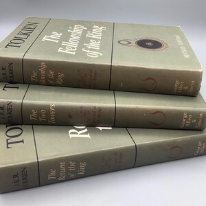 Puede incluir: Tres libros antiguos de J.R.R. Tolkien: "La Comunidad del Anillo", "Las Dos Torres" y "El Retorno del Rey". Los libros tienen una cubierta verde p&aacute;lido con t&iacute;tulos en blanco y rojo. T&iacute;tulos de la serie El Se&ntilde;or de los Anillos.
