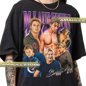 Puede incluir: Camiseta negra con un collage de imágenes de un hombre con cabello rubio. El diseño incluye el texto "Di Laurentis" en morado y "Briar U" en blanco, con gráficos de rayos. La camiseta tiene una estética vintage.