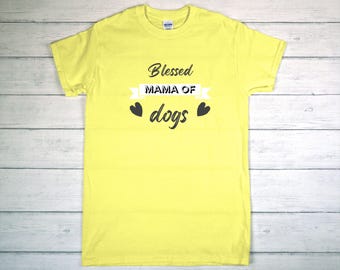 May include: A yellow t-shirt with the text "Blessed MAMA OF dogs" in black script. The text is centered on the shirt, with two black heart graphics. The shirt is made of a soft material.