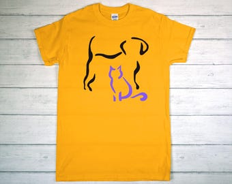 May include: Mustard yellow t-shirt featuring a black dog silhouette and a purple cat silhouette. The dog is standing, and the cat is sitting. The shirt is made of a soft material and is suitable for casual wear.
