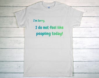 May include: White t-shirt with the text "I'm Sorry. I do not feel like peopling today!" in a gradient of green and blue. The shirt is made of a soft material and has a crew neck.