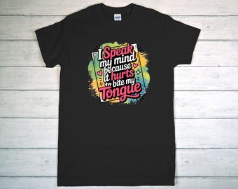 May include: Black t-shirt with the text "I Speak my mind because it hurts to bite my tongue" in a colorful design. The design includes pink, green, yellow, and blue accents. The shirt is displayed on a light wood surface.