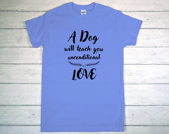 May include: A light blue t-shirt with the text "A Dog will teach you unconditional LOVE" in black script. The text is centered on the shirt, with a decorative sprig design between "unconditional" and "LOVE".