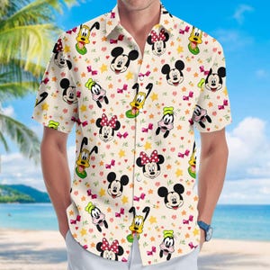 May include: A short-sleeved button-down shirt featuring a cream-colored background with a repeating pattern of Mickey Mouse, Minnie Mouse, Goofy, Pluto, stars, and bows. The shirt has a classic collar and is worn by a person.