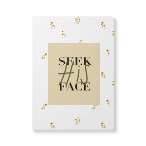 May include: A white notebook with a beige rectangle in the center. The rectangle has the text "SEEK HIS FACE" in black and green lettering. The notebook is covered in a pattern of small yellow flowers.