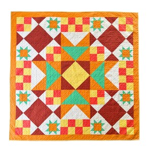 Op de afbeelding: Een kleurrijke quilt met een geometrisch patroon. De quilt heeft een centraal sterrenpatroon in geel, groenblauw en oranje, omgeven door vierkanten en ruiten in verschillende kleuren. De rand is effen oranje. De quilt is machinaal gestikt.