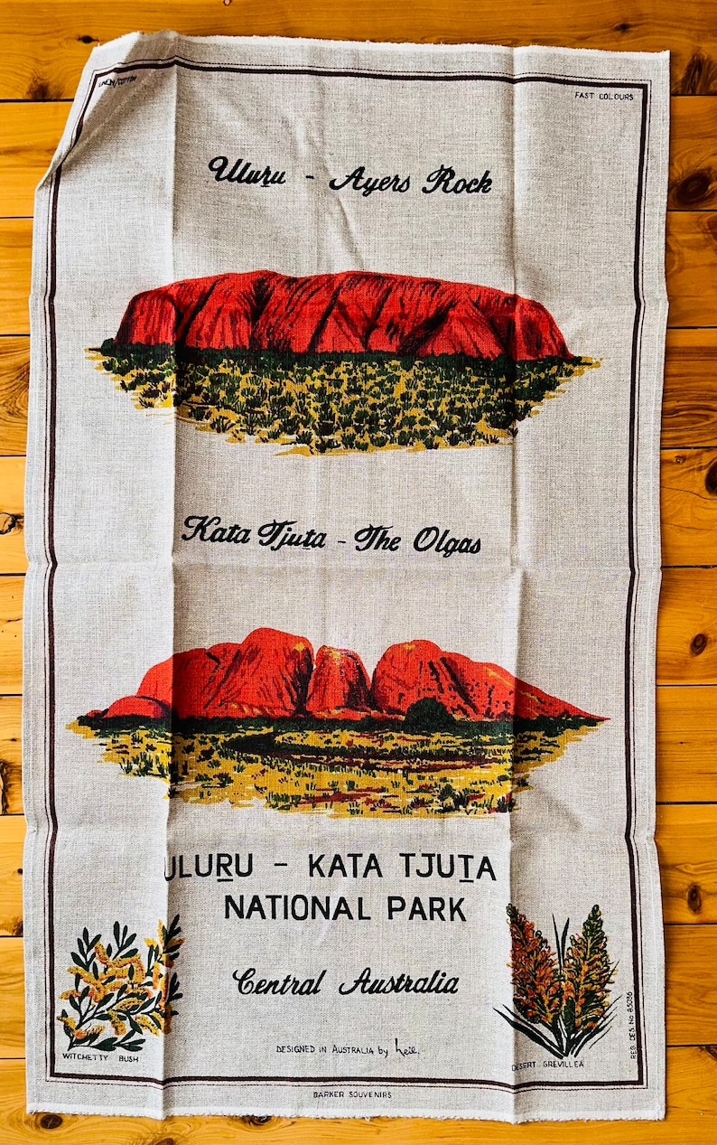 Op de afbeelding: Een theedoek met een beige achtergrond met illustraties van Uluru en Kata Tjuta, ook bekend als Ayers Rock en The Olgas, in Centraal-Australi&euml;. De tekst "Uluru - Kata Tjuta National Park, Central Australia" is op de theedoek gedrukt.