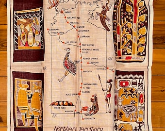 Puede incluir: Un paño de cocina de lino vintage con un mapa del Territorio del Norte de Australia con varias ciudades y pueblos marcados. El mapa está rodeado de diseños de arte aborigen estilizados en rojo, marrón y amarillo.