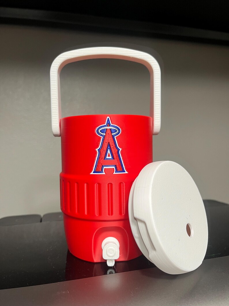 K&ouml;nnte beinhalten: Ein roter Wasserk&uuml;hler mit wei&szlig;em Griff und Deckel. Der K&uuml;hler hat das Logo der Los Angeles Angels in Blau und Wei&szlig;. Der Deckel ist zur Seite.