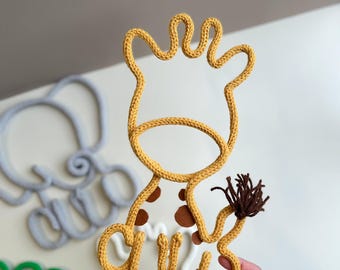 May include: A yellow knitted giraffe wall hanging with brown spots and a brown tail. The giraffe is made of yarn and is a cute and whimsical decoration for a child's room.