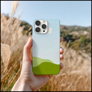 May include: A light blue phone case with a landscape design. The case features a gradient of colors, transitioning from light blue to white and then to green. The phone case has a camera module with three lenses.