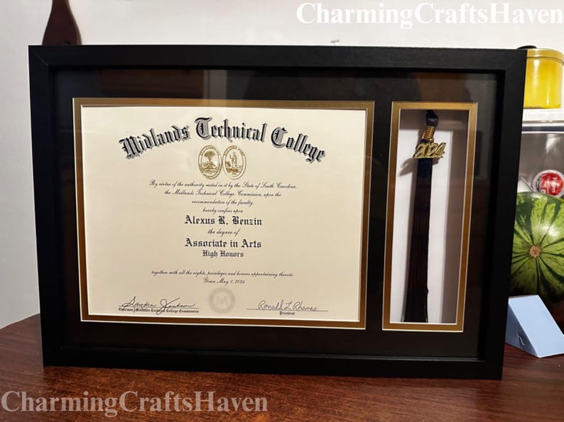 May include: A framed diploma from Midlands Technical College, featuring the name Alexus R. Benzin and the degree of Associate in Arts. The frame includes a compartment with a graduation tassel with a 2024 charm. The frame is black.
