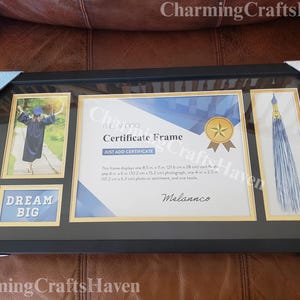 May include: Black certificate frame with gold accents, holding a graduation photo, certificate, and tassel. The frame includes the text "DREAM BIG" and "Certificate Frame". The frame displays one 8.5 in x 11 in (21.6 cm x 28 cm) certificate.